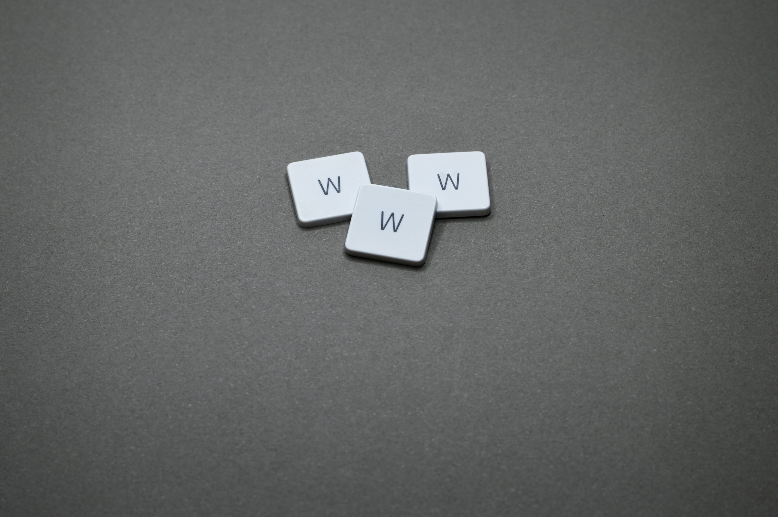 Three Scrabble tiles forming the letters WWW (World Wide Web) on a dark grey background signifying SEO
